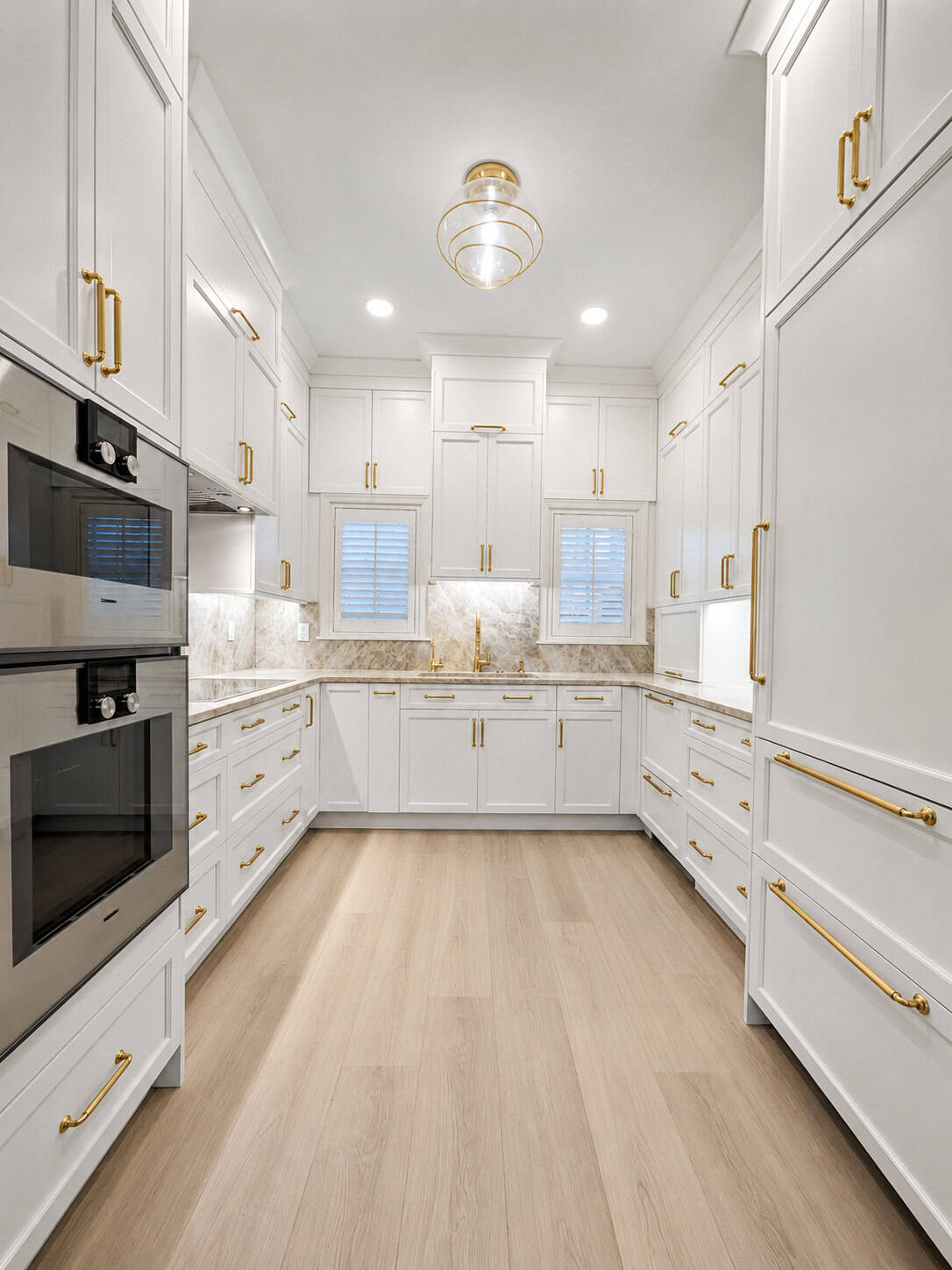Full view of a Boca Raton kitchen remodel with white Holiday shaker cabinets, brass hardware, and Taj Mahal quartzite countertops.