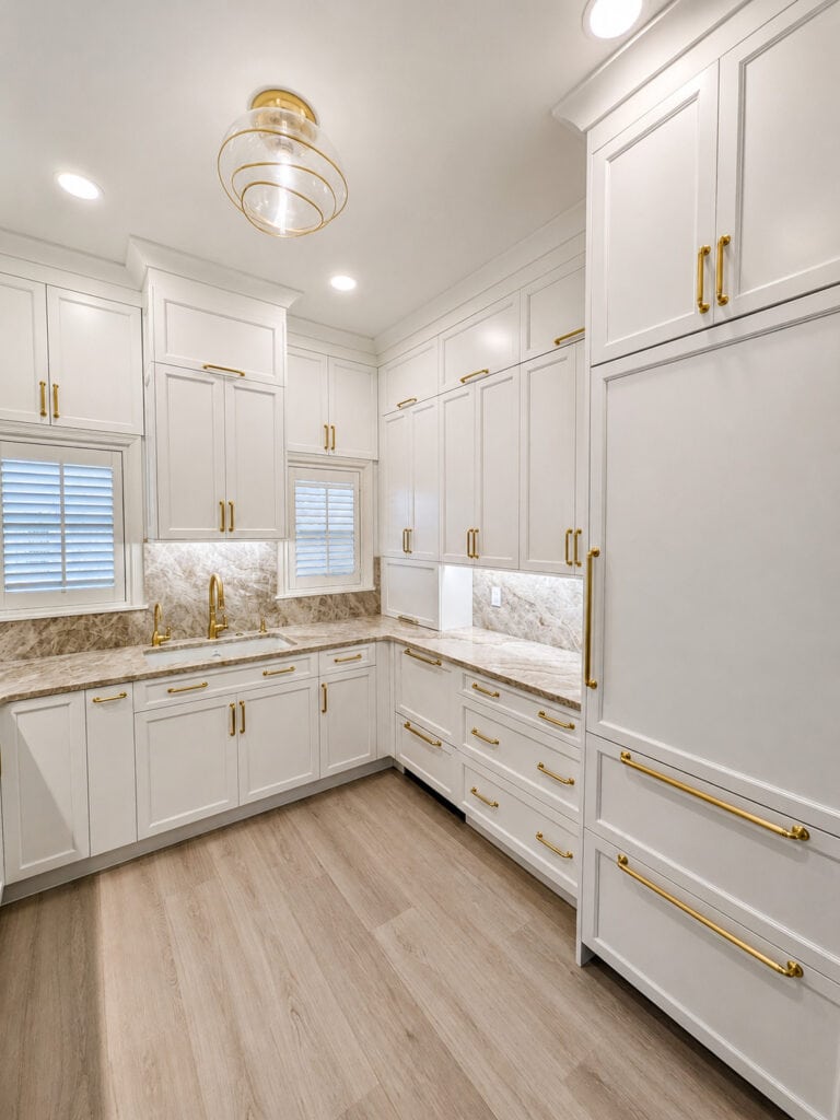 Boca Raton kitchen remodel with a Taj Mahal quartzite counter, brass gooseneck faucet, and panel-front refrigerator.