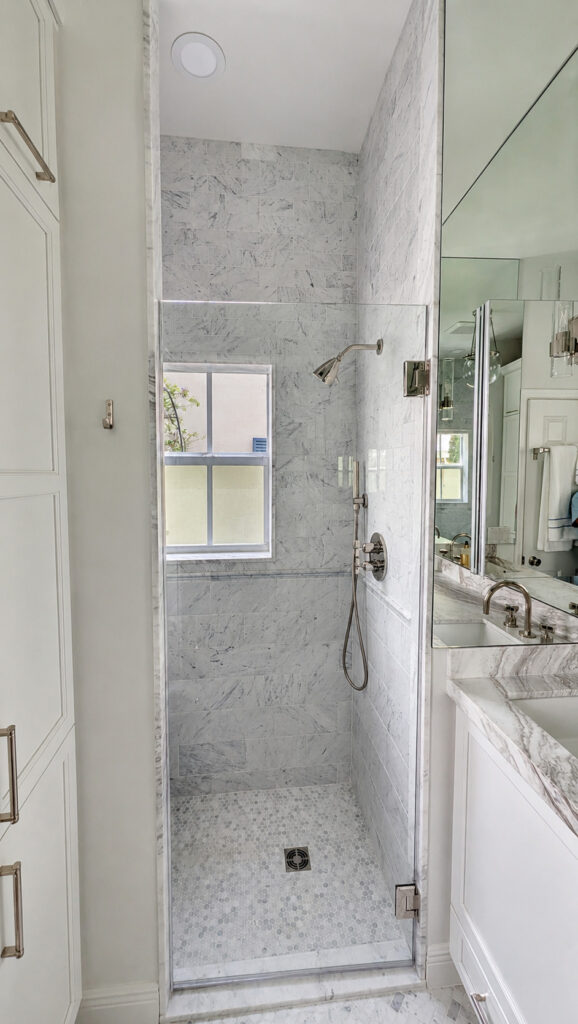 Boca Raton bathroom remodel with a frameless glass walk-in shower, marble tile walls, and a marble hexagon mosaic floor.