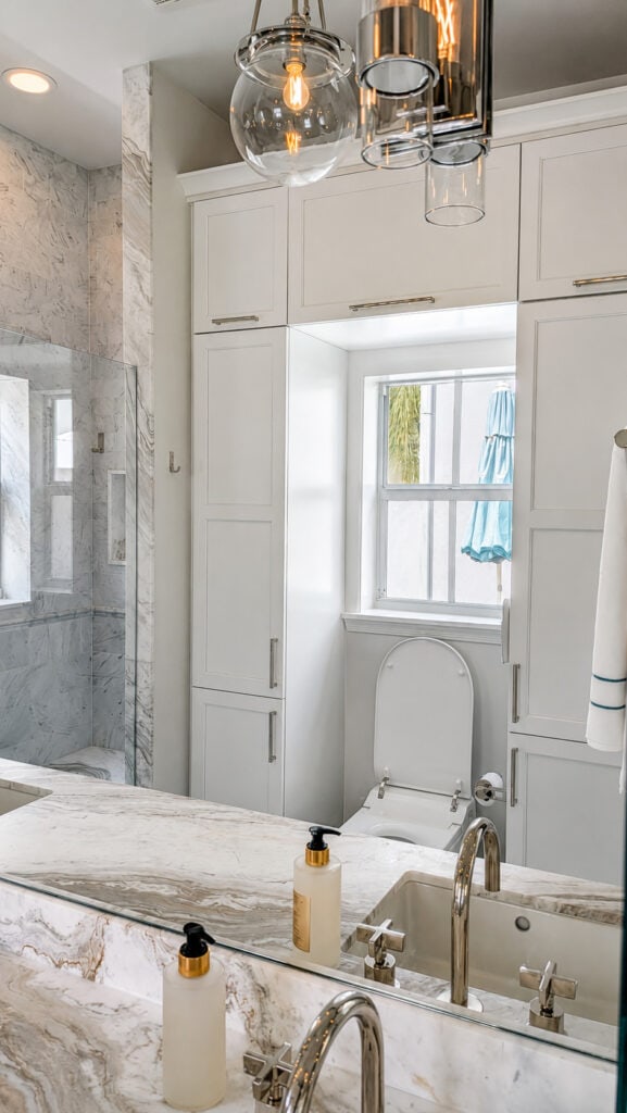 Boca Raton bathroom remodel with floor-to-ceiling white shaker storage cabinetry and a quartzite vanity with polished nickel fixtures.