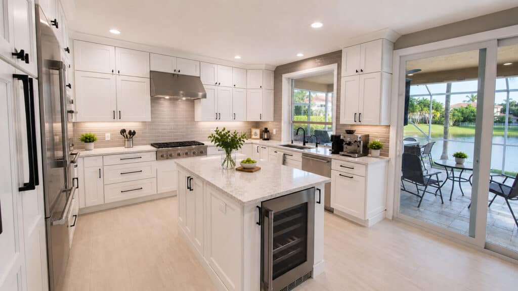 Jupiter kitchen remodel with white shaker cabinets, a quartz island, and sliding doors opening to a screened lanai with a lake view.