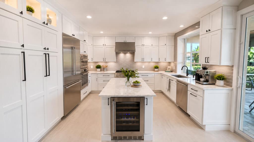 Jupiter luxury kitchen with full-height white shaker cabinets, black hardware, a quartz island with wine fridge, double wall ovens, and a gas cooktop.