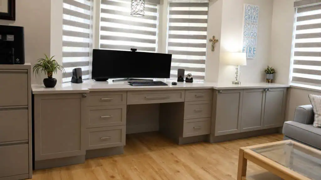 Lake Worth home office with a grey built-in desk, quartz counter, a file cabinet, and a bay window with layered shades.