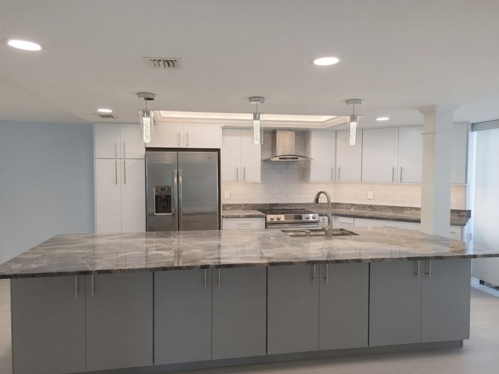Open-concept North Palm Beach kitchen with a quartz peninsula and island, white cabinets, and columns dividing the open living space.