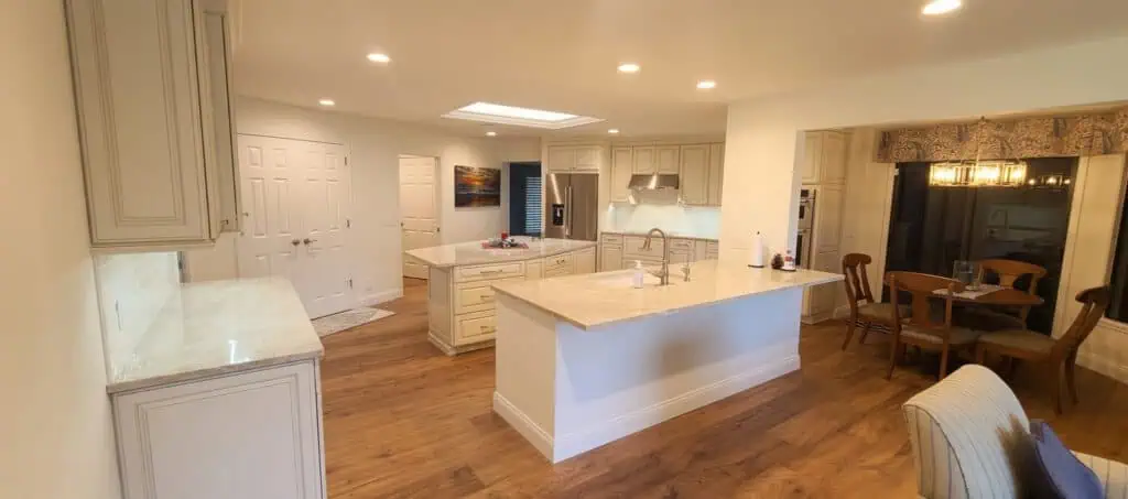 PGA National open kitchen with cream cabinets, two quartz islands, wood floors, a skylight, and an adjoining dining area.