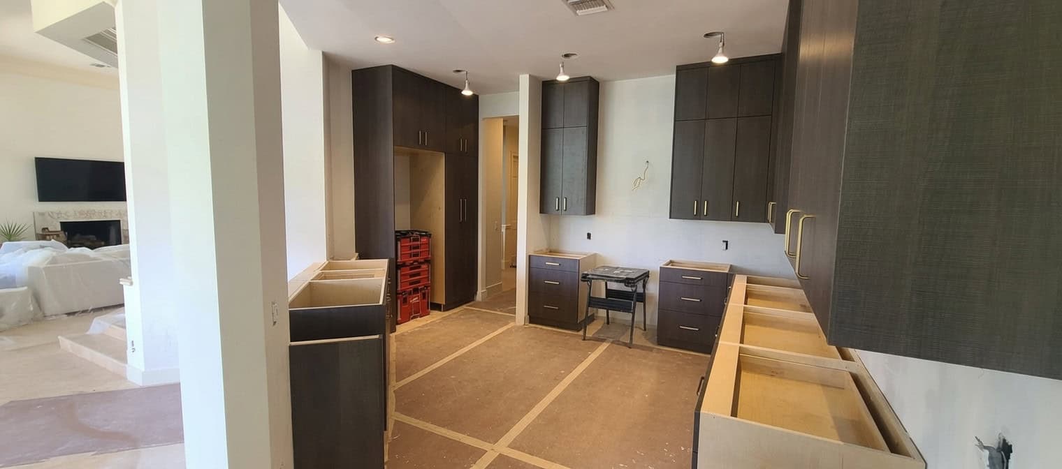 A cabinet installation in progress with kraft-paper floor protection and organized modular tool crates during a home remodel.