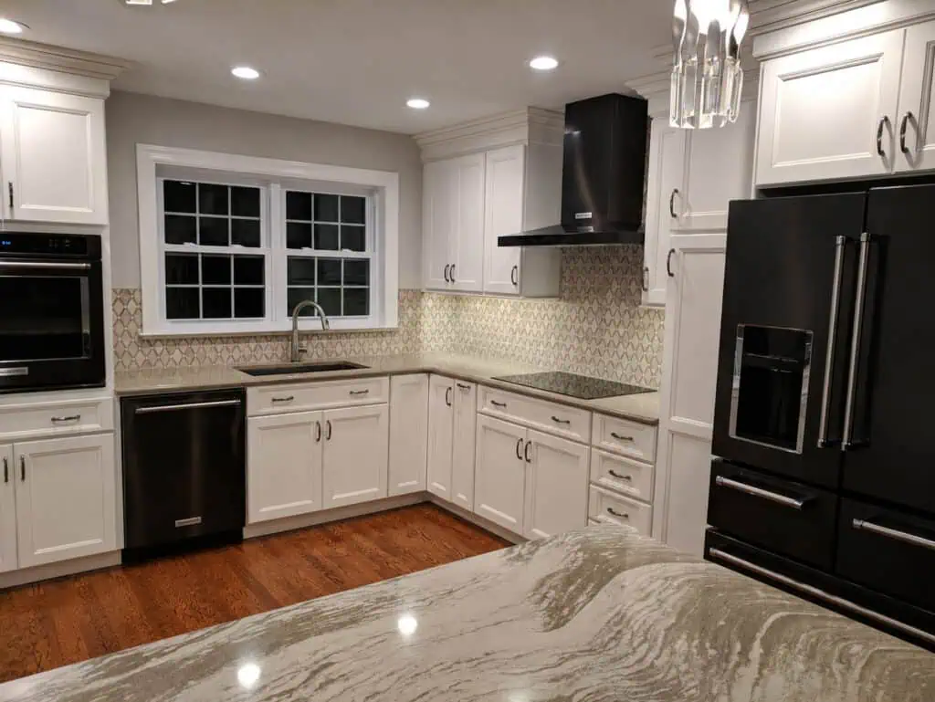 Timeless transitional kitchen with glazed cream cabinets, an arabesque mosaic backsplash, black stainless appliances, and quartz counters.