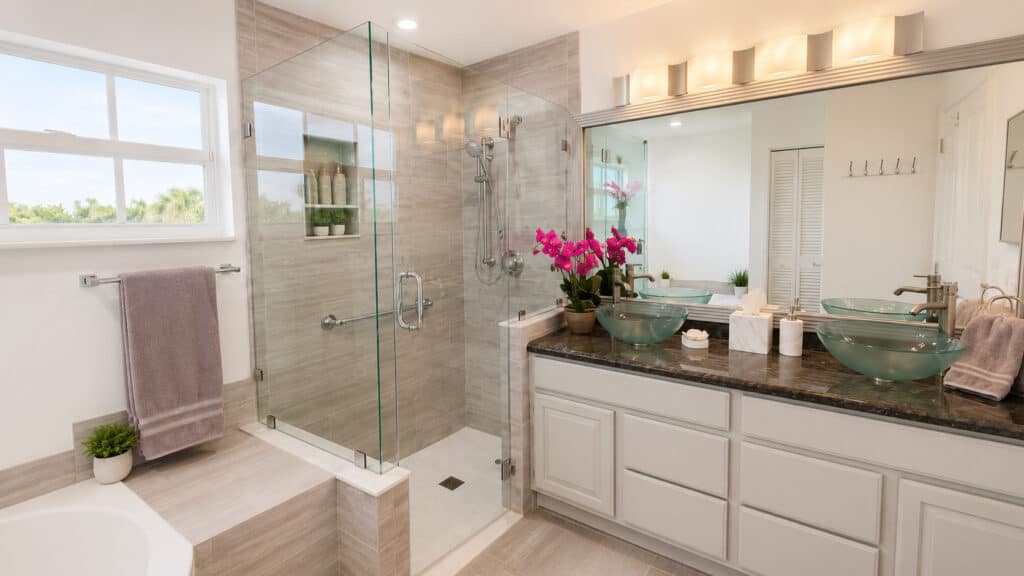 Wellington primary bathroom with a corner soaking tub, a grey wood-look tile walk-in shower with a teak seat, and a double vanity.