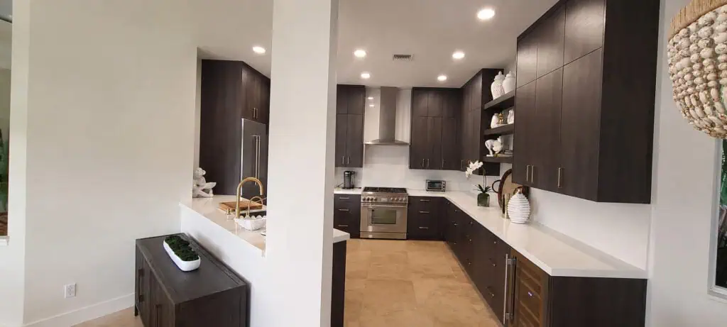 West Palm Beach Ibis modern kitchen with dark wood flat-panel cabinets, brass hardware, white quartz counters, and a stainless range.