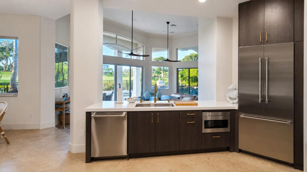 West Palm Beach Ibis kitchen peninsula with white quartz and dark wood cabinets, opening to a living area with a golf-course view.