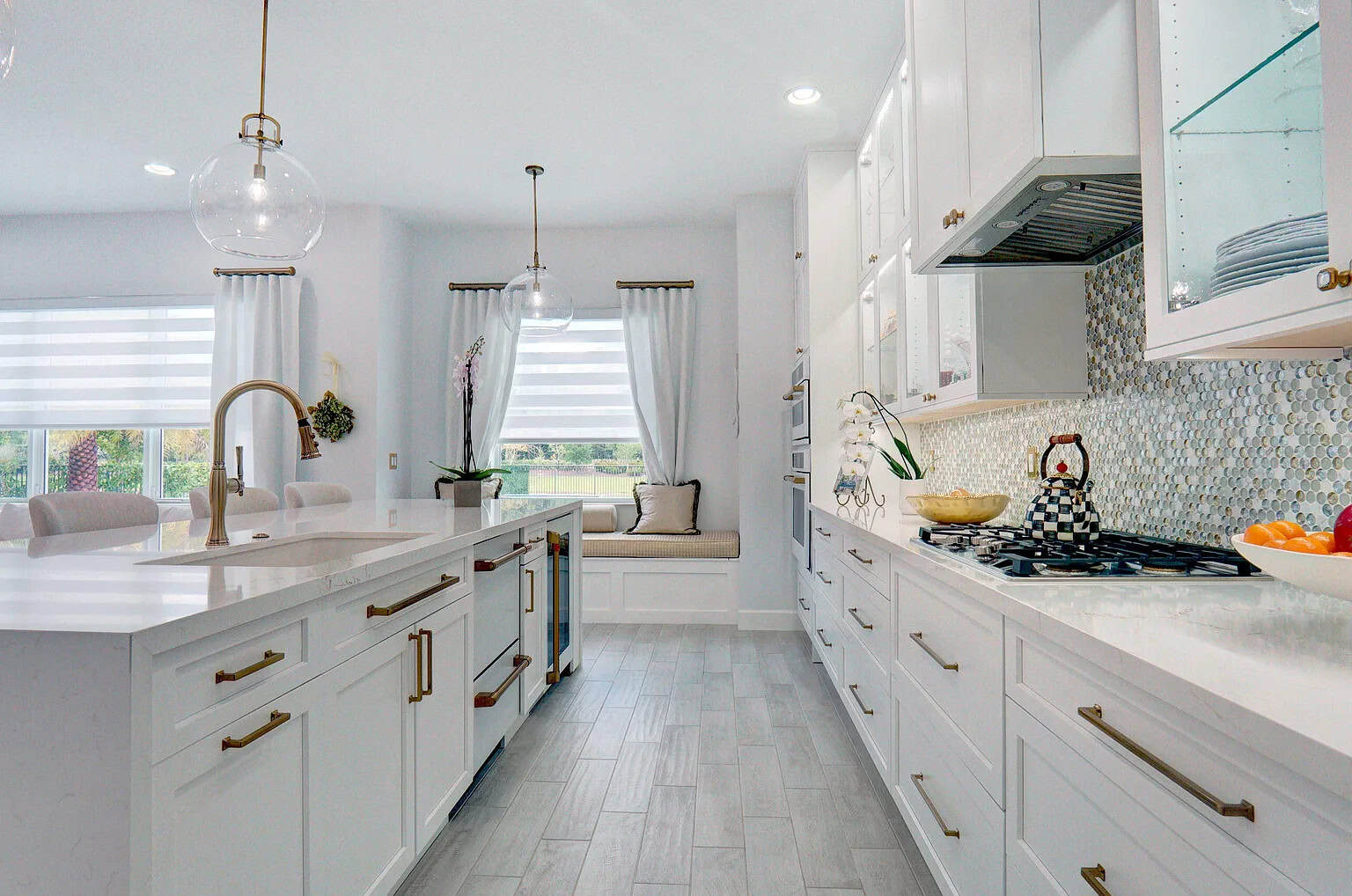 Palm Beach County luxury kitchen with white shaker cabinets, brass hardware, a quartz island, and a pearl mosaic backsplash.
