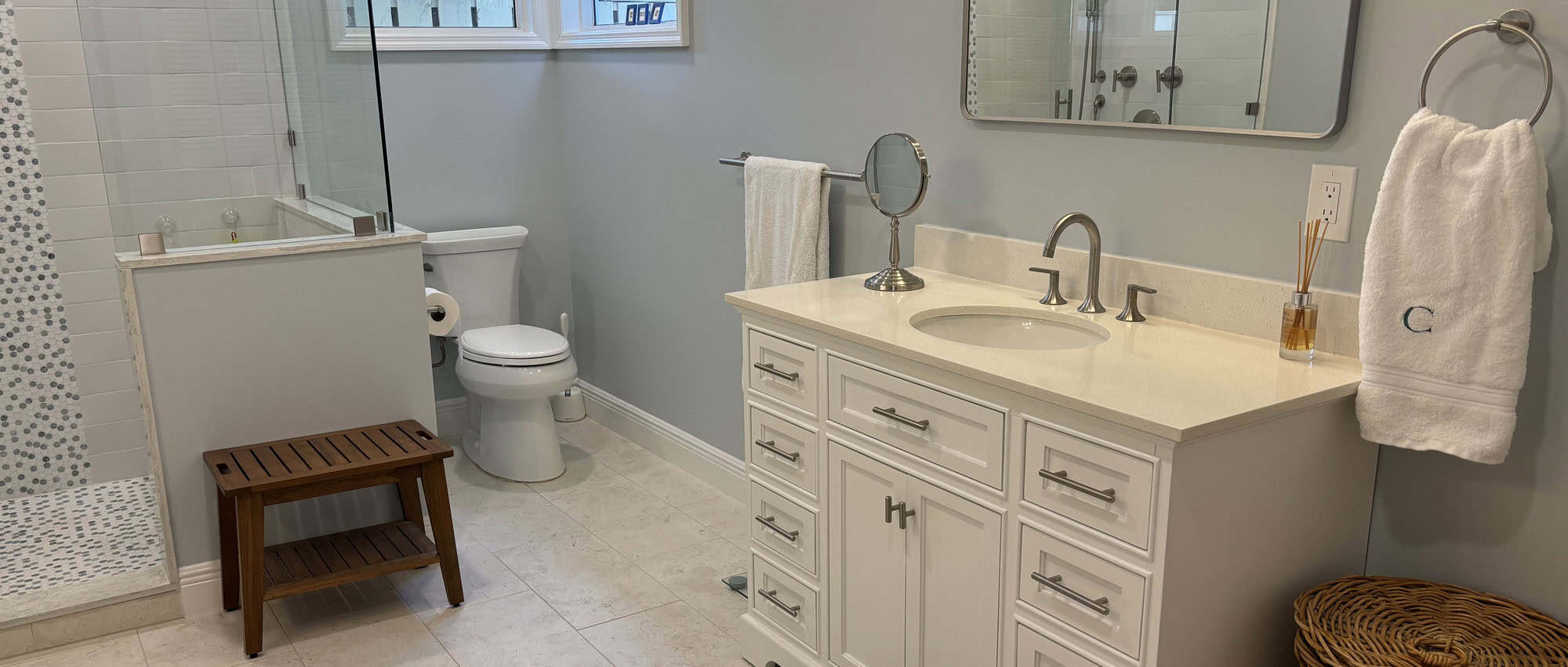 Palm Beach Gardens PGA bathroom remodel with a white vanity, framed mirror and glass walk-in shower with mosaic tile accent